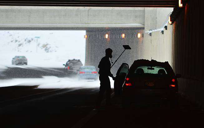 A driver returns to his car after stooping beneath Hagerstown Regional Airport runway to clear his windows Sunday, Dec. 8, 2013. A powerful storm that crept across the country dumped a mix of snow, freezing rain and sleet on the Mid-Atlantic region and headed northeast Sunday, turning NFL playing fields in Pennsylvania into winter wonderlands, threatening as much as a foot of snow in Delaware and New Jersey and raising concerns about a messy morning commute. (AP Photo/The Herald-Mail, Kevin G. Gilbert)